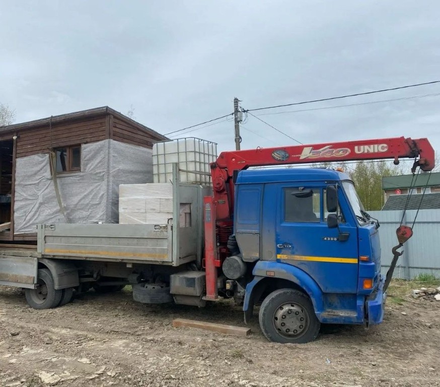 Синий манипулятор со стрелой UNIC ставит бытовку